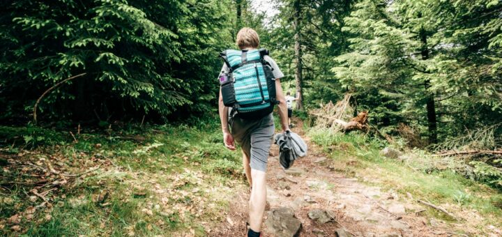 Zdjęcie przedstawiające mężczyznę z plecakiem w lesie